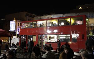 Autobus rouge typique de Londres le soir entouré de monde